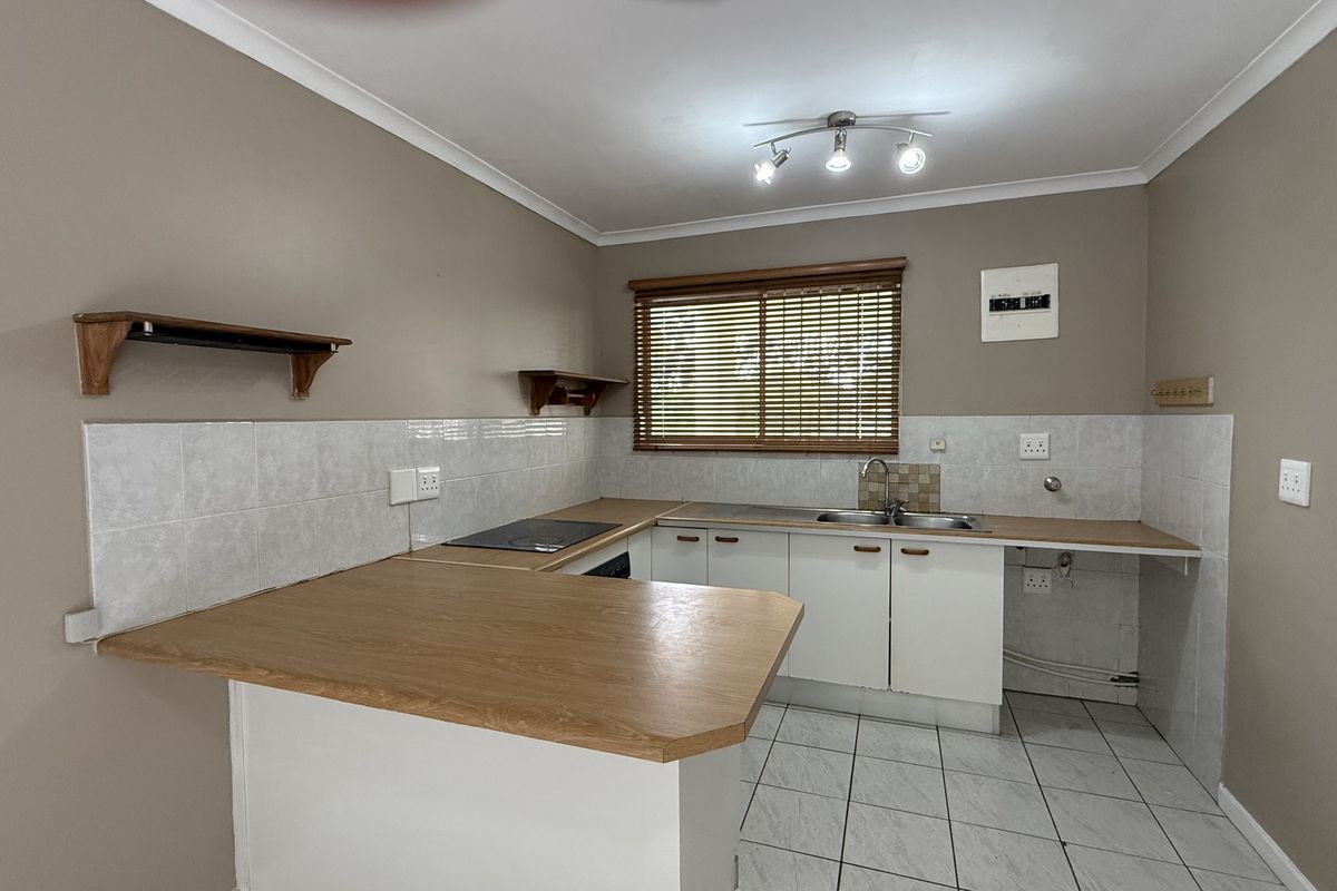 A functional kitchen featuring built-in cabinetry, laminate countertops, a stainless steel sink, and ceramic tile flooring, offering a clean and practical workspace.