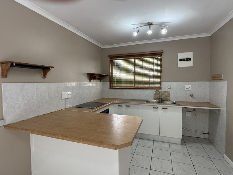 A functional kitchen featuring built-in cabinetry, laminate countertops, a stainless steel sink, and ceramic tile flooring, offering a clean and practical workspace.