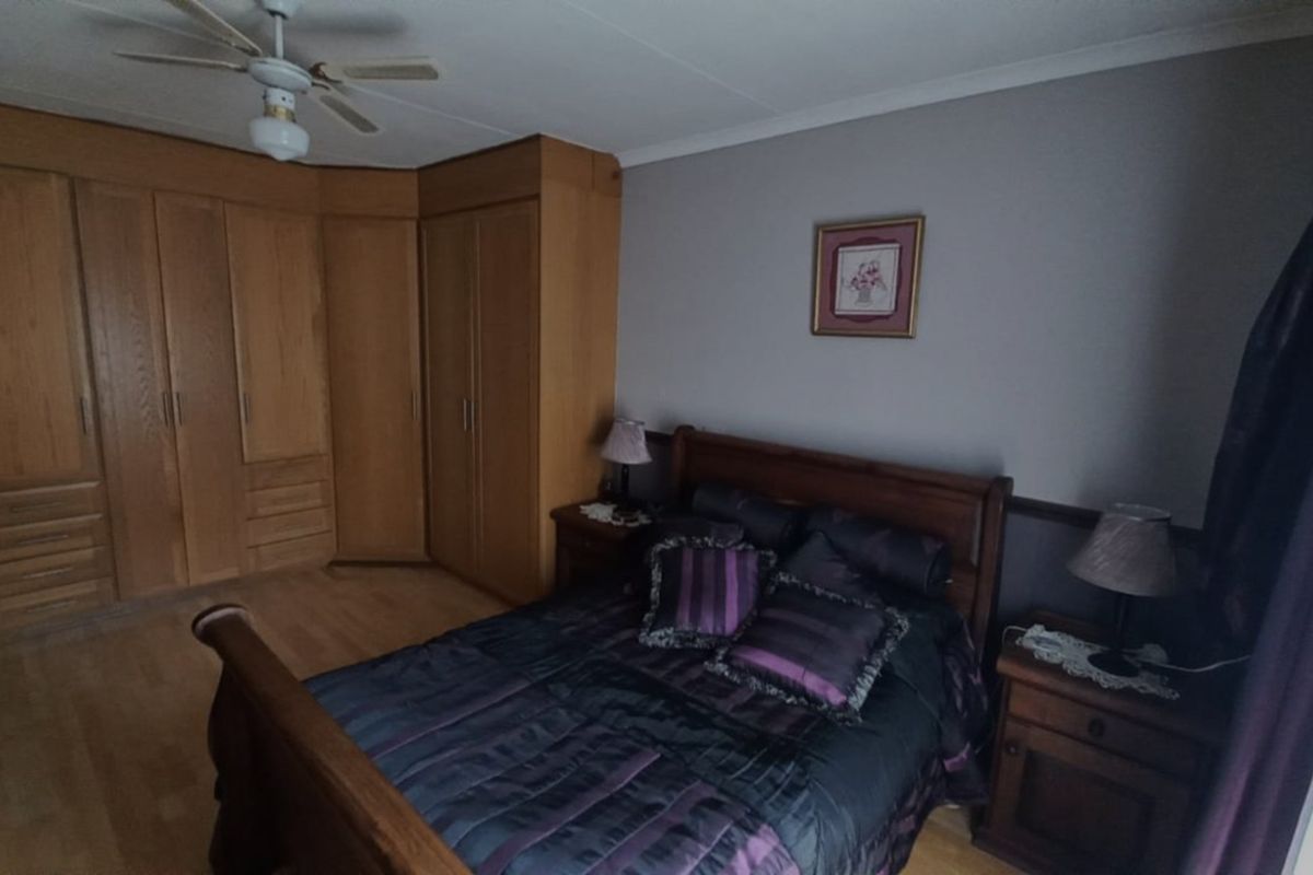 A bedroom featuring built-in wooden cabinetry, a ceiling fan, and laminate flooring.