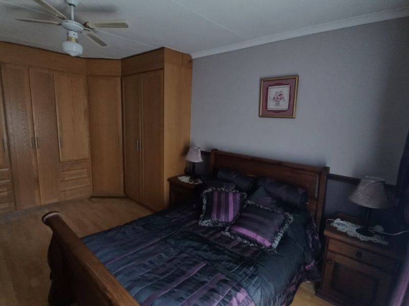 A bedroom featuring built-in wooden cabinetry, a ceiling fan, and laminate flooring.
