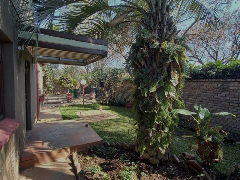 A rear garden area featuring a paved patio, a covered awning, and a brick boundary wall, providing a private outdoor space.