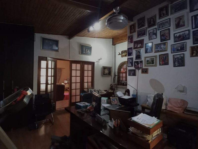 A home office space featuring timber ceilings with exposed beams, laminate flooring, and double french doors leading to an adjacent room.