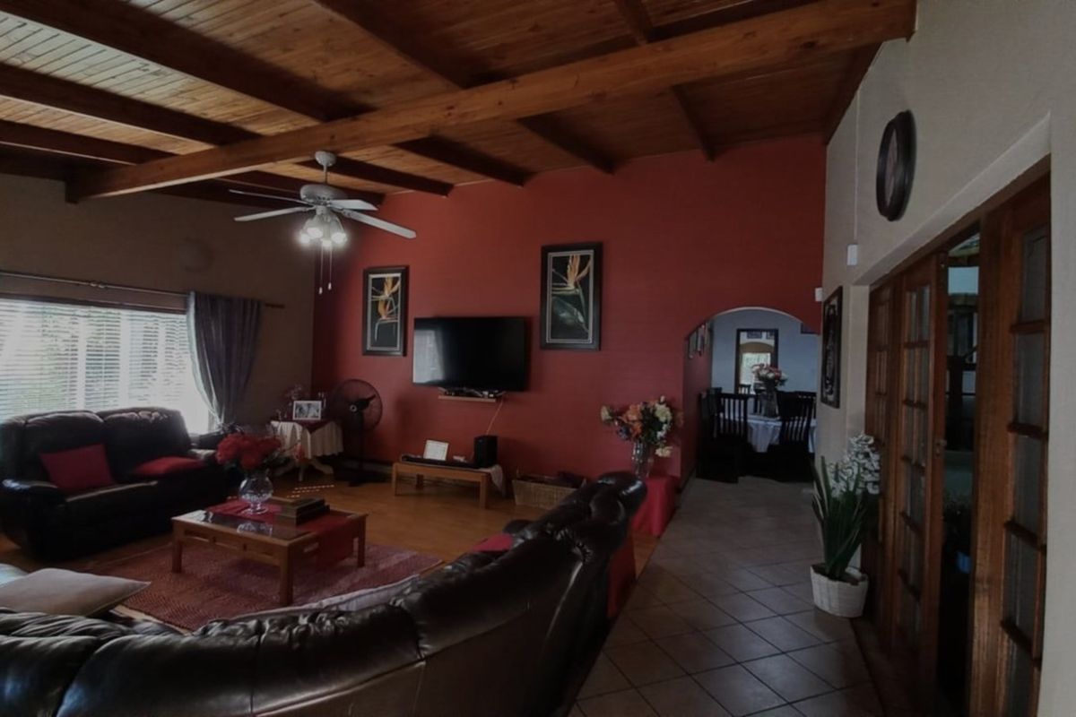 Spacious living room featuring an exposed timber beam ceiling, tiled flooring, and an archway leading to the dining area.