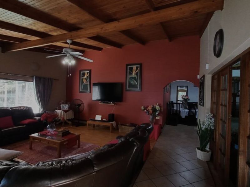 Spacious living room featuring an exposed timber beam ceiling, tiled flooring, and an archway leading to the dining area.