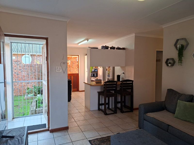 Open plan living area featuring tiled flooring, a breakfast bar, and direct access to an outdoor patio area through a security gate.
