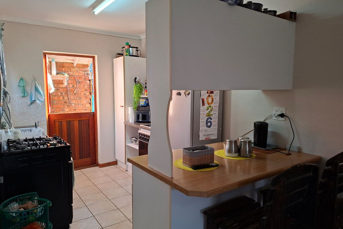 A functional kitchen featuring a breakfast bar, tiled flooring, and a gas stove, with direct access to an exterior brick-walled area.
