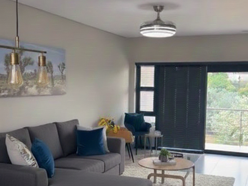 Modern open-plan living area featuring tiled floors, contemporary pendant lighting, a ceiling fan, and large sliding doors leading to an outdoor space.