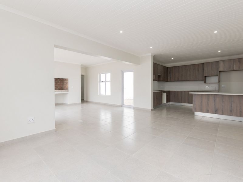 Spacious open-plan living area featuring a modern kitchen with built-in cabinetry, tiled flooring, and a dedicated indoor braai area.