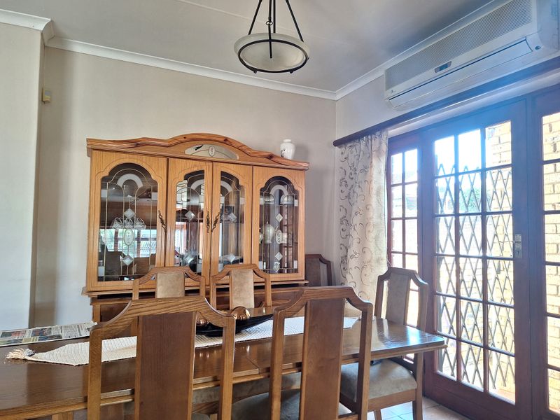 A dining room featuring a split-system air conditioner, coving, and timber-framed glass doors providing access to the exterior.