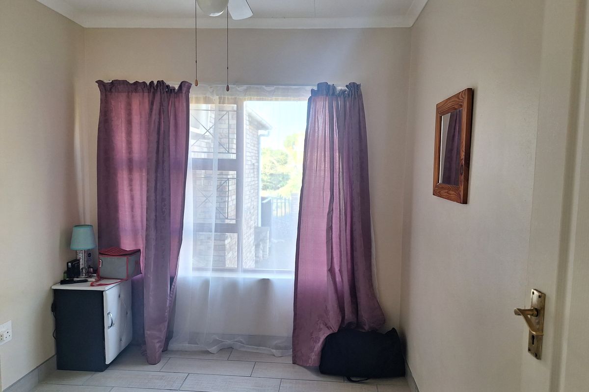 A bedroom featuring tiled flooring, a ceiling fan, and a window with natural light.