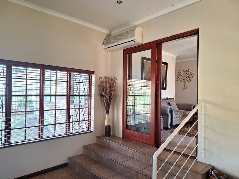 An inviting entrance area featuring tiled steps, a wooden sliding door, and a wall-mounted air conditioning unit, leading into the main living space.
