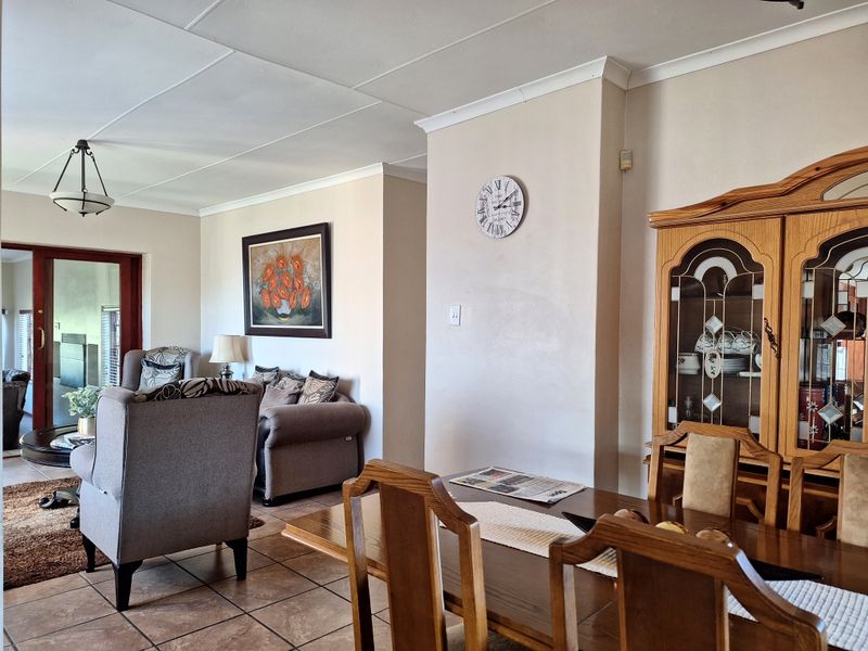 Open plan living and dining area featuring tiled flooring, neutral wall finishes, and a sliding door leading to an outdoor space.