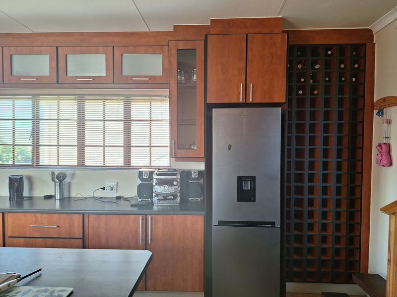 Kitchen area featuring wood-finish cabinetry, dark laminate countertops, and a dedicated built-in wine rack storage unit.