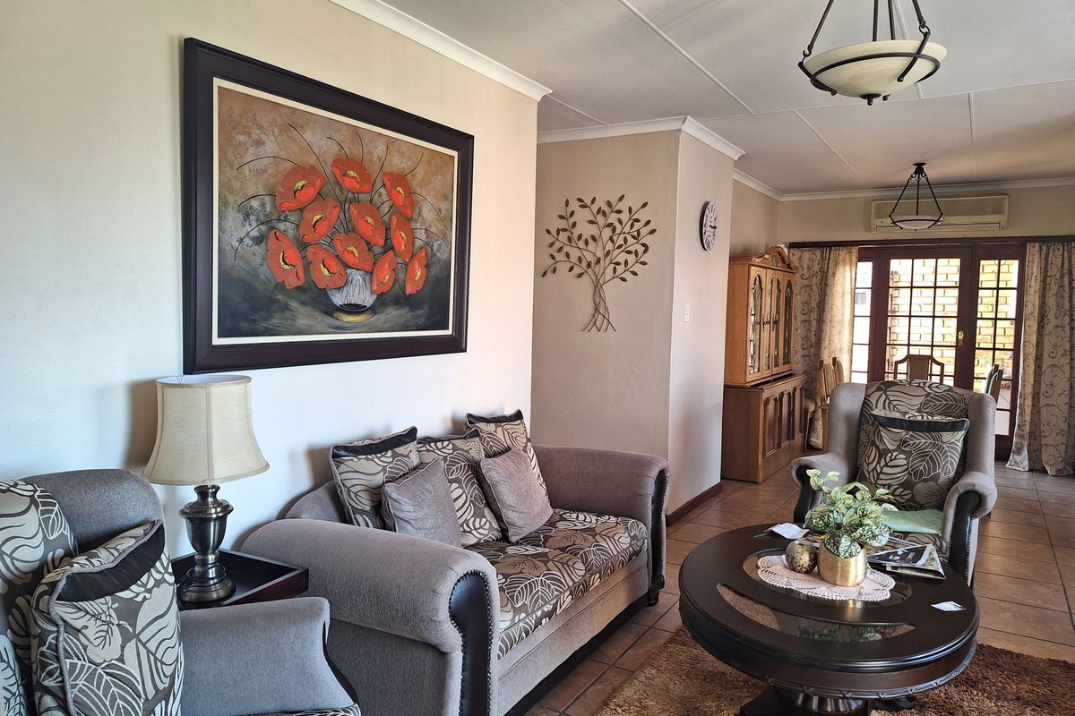 A comfortable living room featuring tiled flooring, coved ceilings, and a split-system air conditioner, with direct access to an outdoor area through sliding glass doors.