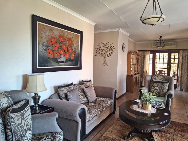 A comfortable living room featuring tiled flooring, coved ceilings, and a split-system air conditioner, with direct access to an outdoor area through sliding glass doors.