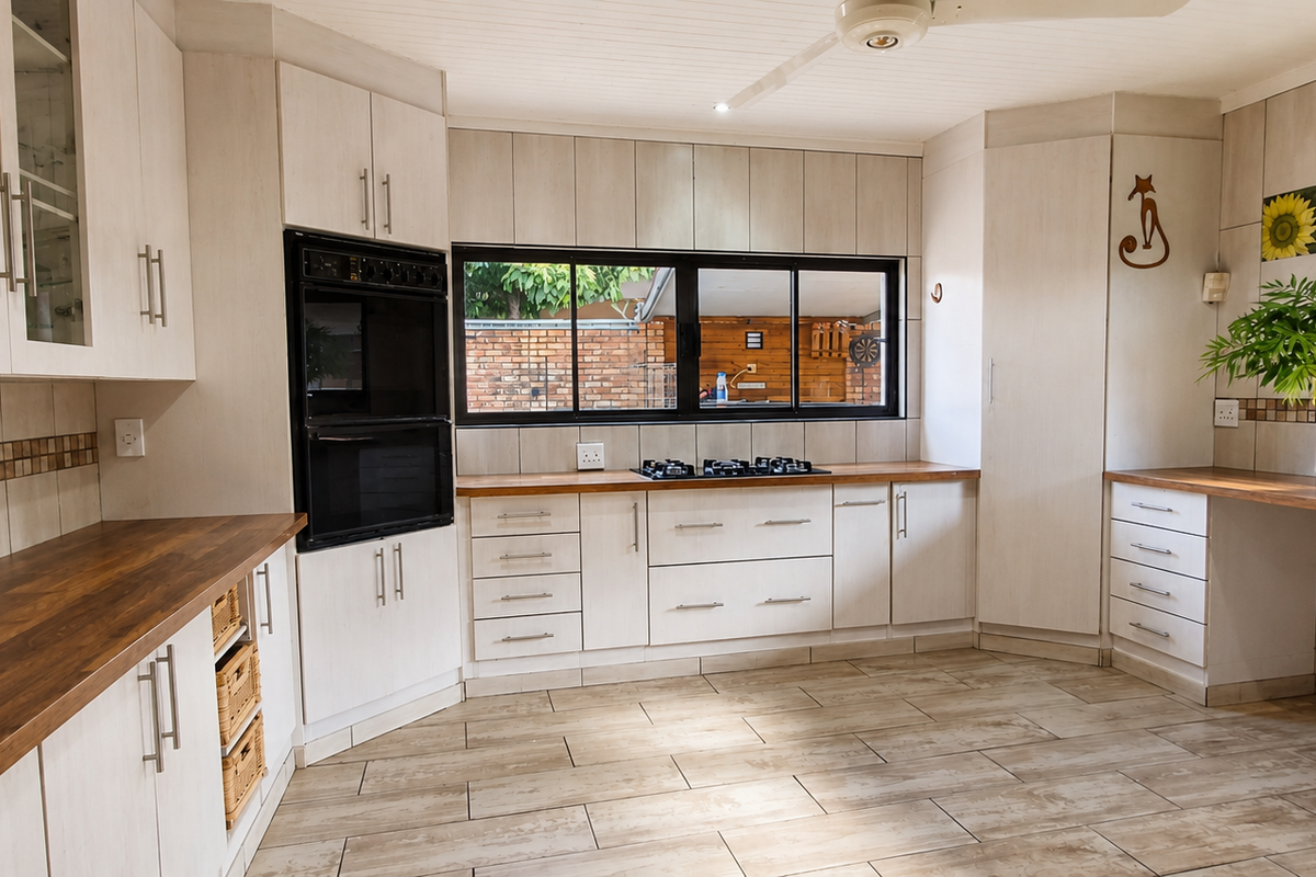 A spacious kitchen featuring light-toned cabinetry, dark laminate countertops, a built-in oven, gas hob, and tiled flooring with a neutral backsplash.