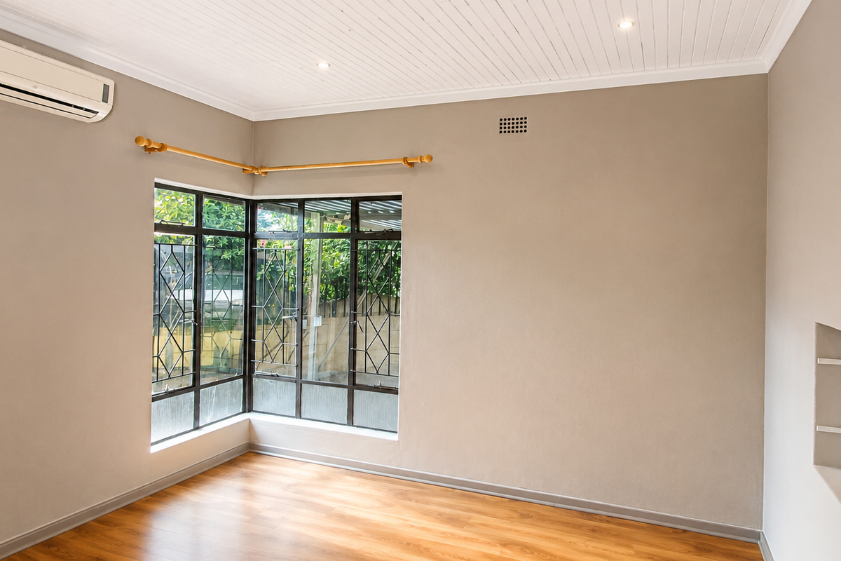 A bright, empty bedroom featuring laminate flooring, a split-system air conditioner, corner windows, and a unique recessed wall shelf.