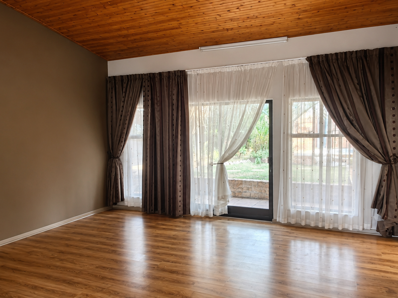 Spacious living room featuring laminate flooring, a timber-paneled ceiling, split-system air conditioning, and sliding glass doors providing access to the rear garden.