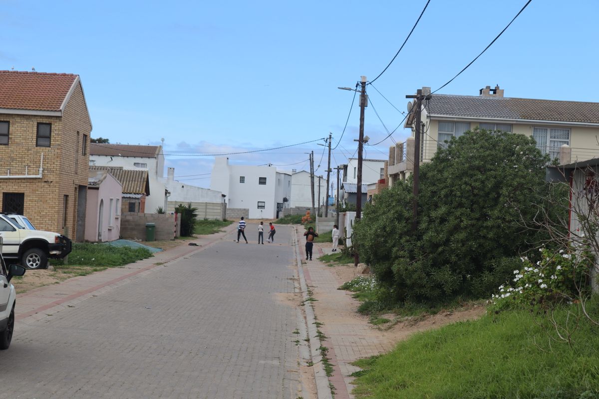 A view of a residential street featuring paved roads, overhead utility lines, and surrounding residential properties.