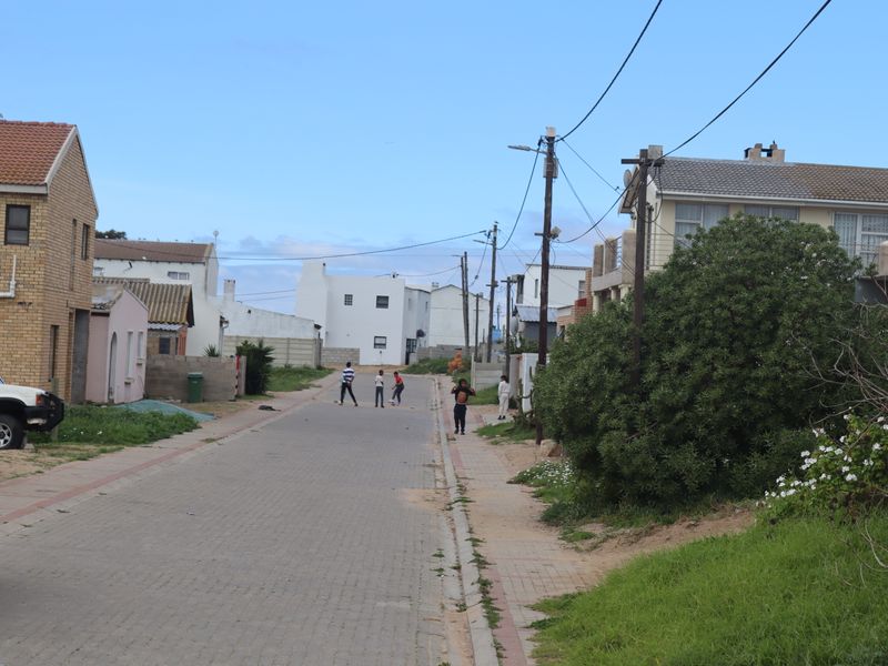A view of a residential street featuring paved roads, overhead utility lines, and surrounding residential properties.