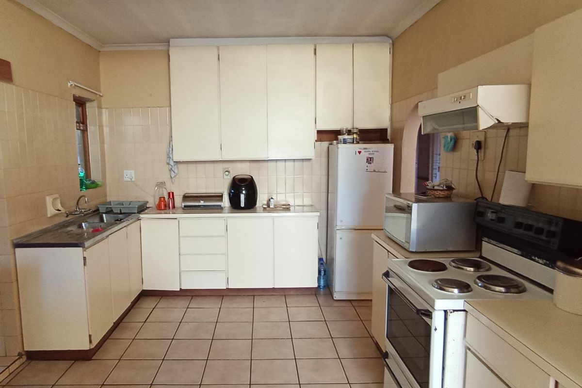 A functional kitchen featuring dated cabinetry, tiled backsplash, and tiled flooring, offering a blank canvas for modern renovation and aesthetic updates.
