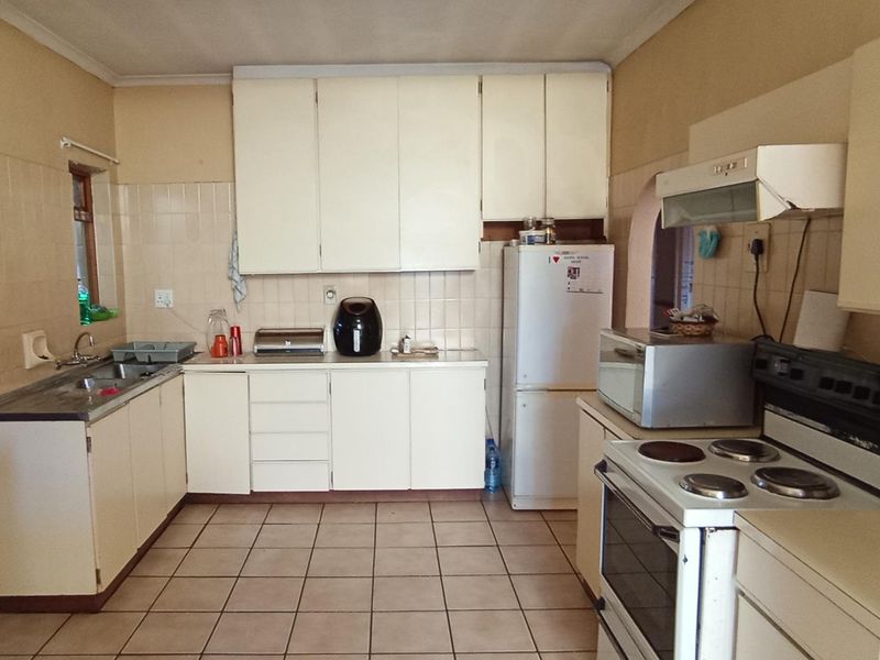 A functional kitchen featuring dated cabinetry, tiled backsplash, and tiled flooring, offering a blank canvas for modern renovation and aesthetic updates.