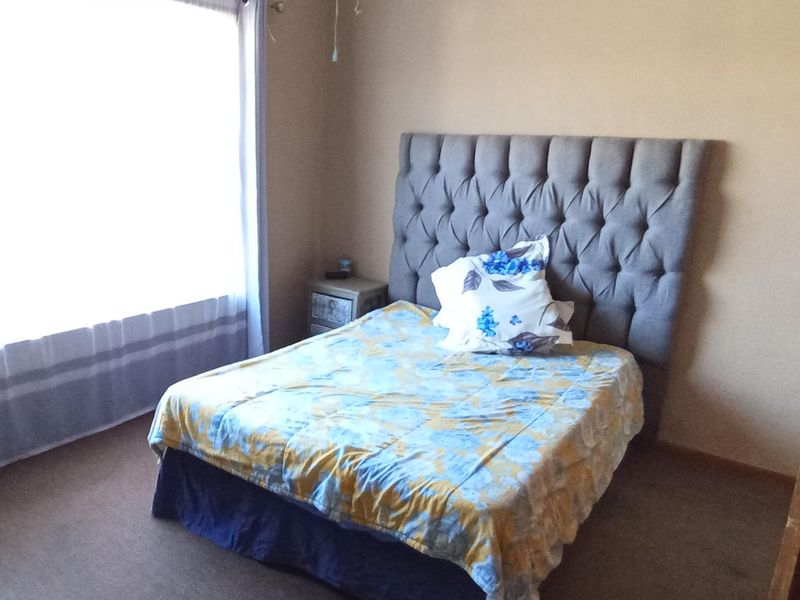 A standard bedroom featuring carpeted flooring and a large window allowing for natural light.