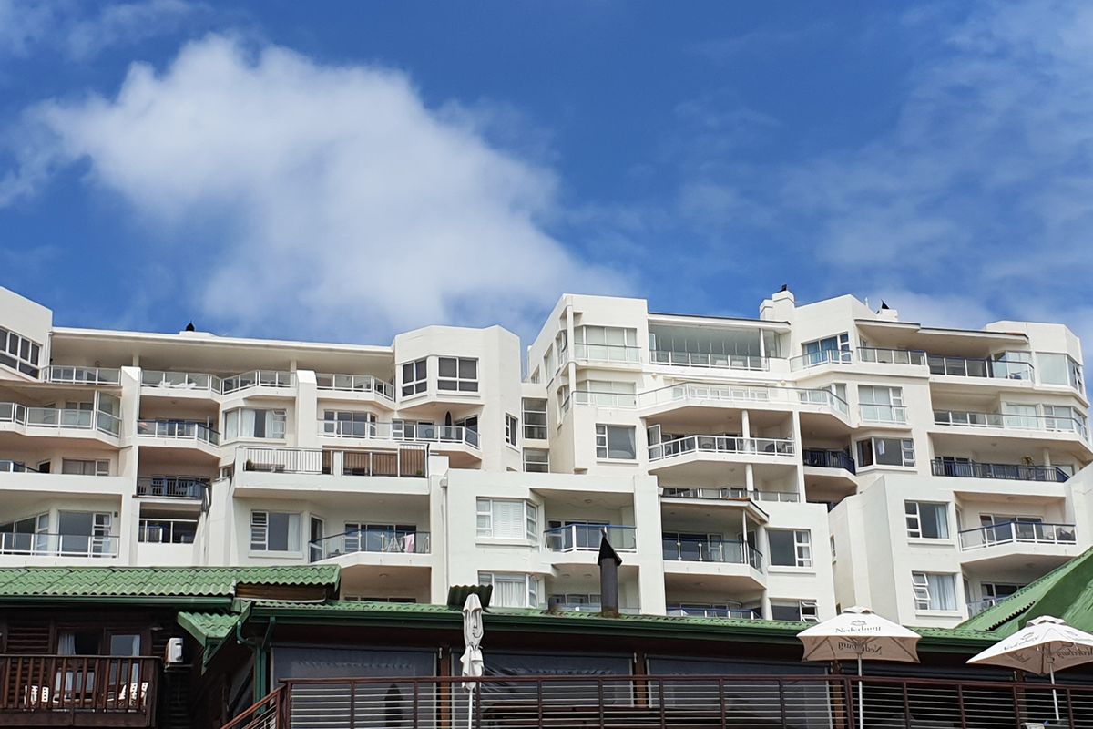 A view of the rear elevation of a multi-story apartment complex featuring tiered balconies with glass and metal railings.