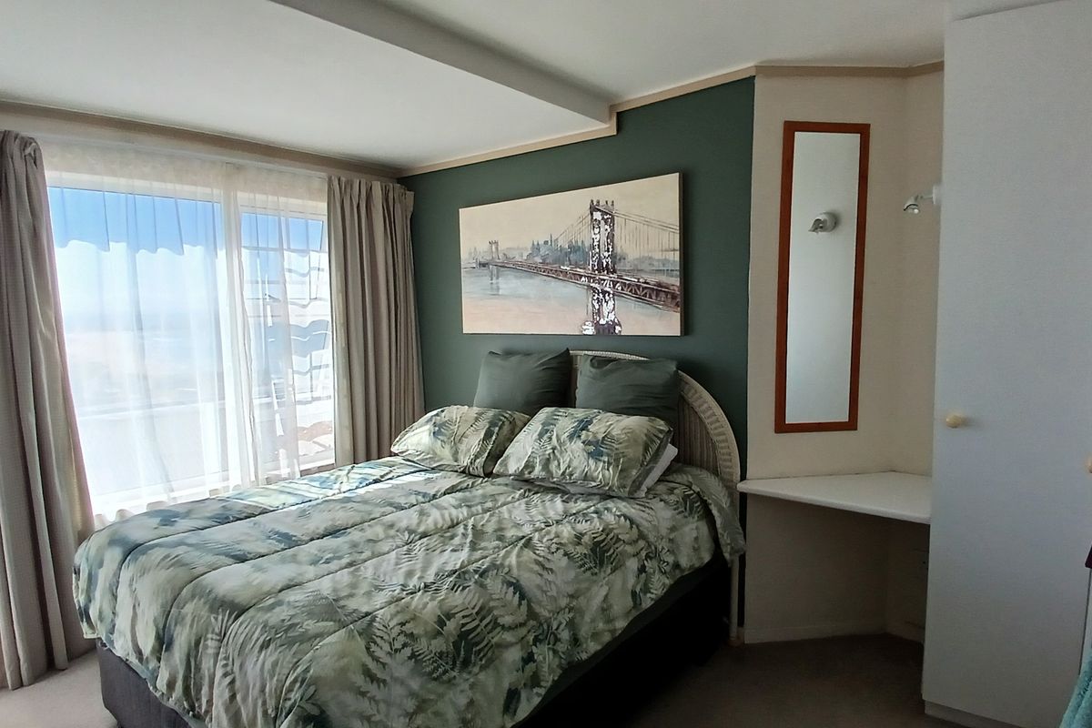A bedroom featuring a built-in wardrobe, integrated vanity area, and sliding glass doors that provide natural light and access to the exterior.