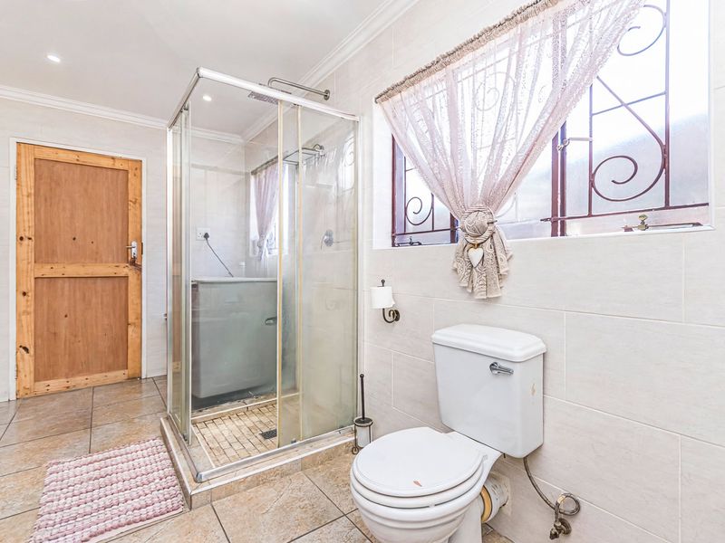 A functional bathroom featuring a glass shower enclosure, toilet, and neutral tiled finishes throughout, providing a clean and practical space.