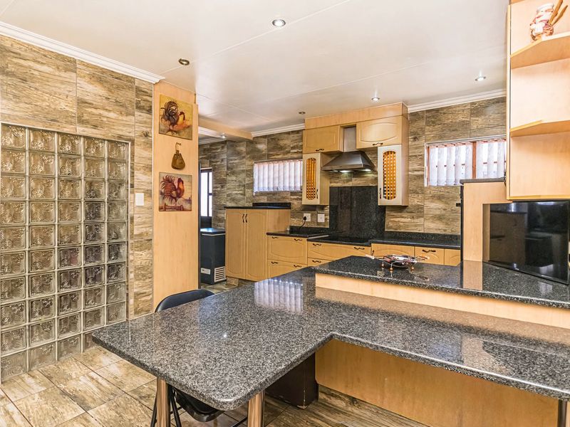 A spacious kitchen featuring granite countertops, extensive built-in cabinetry, a unique glass block wall feature, and modern recessed lighting.