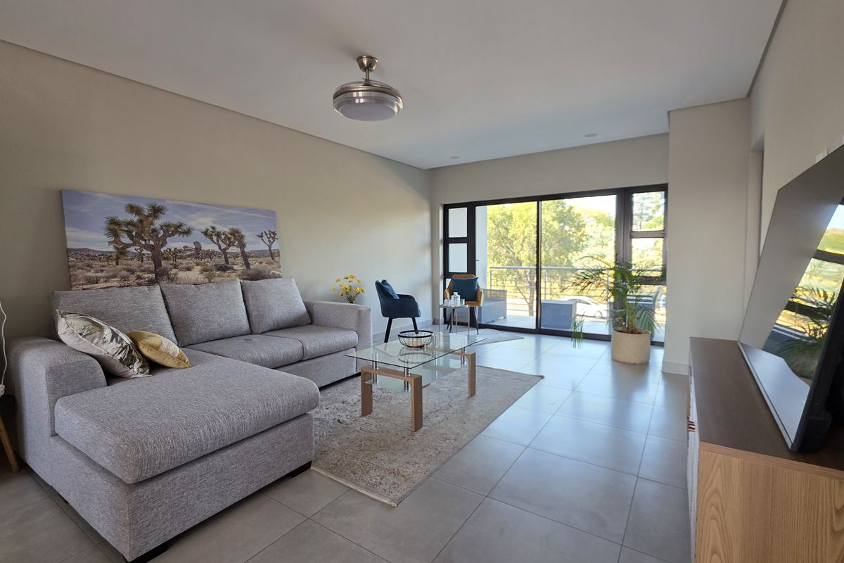 A bright and spacious living room featuring large sliding glass doors that provide natural light and access to an outdoor balcony area.