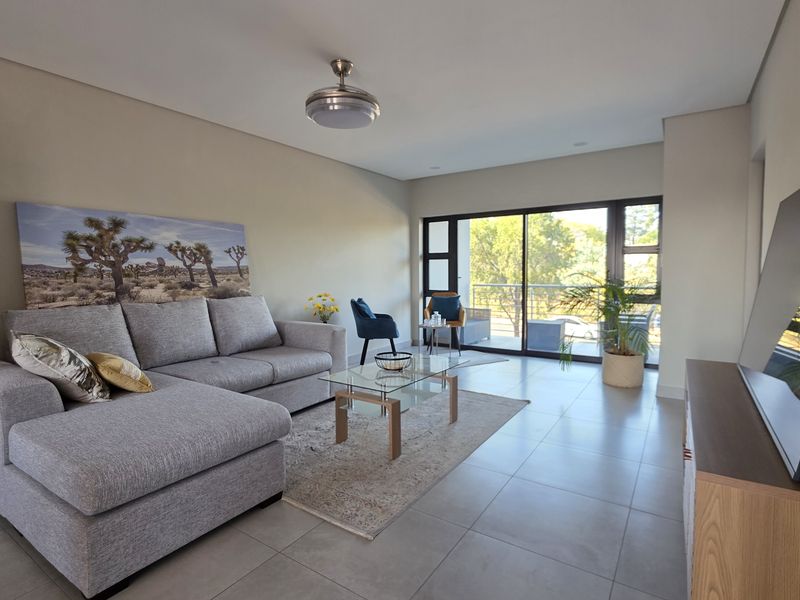 A bright and spacious living room featuring large sliding glass doors that provide natural light and access to an outdoor balcony area.