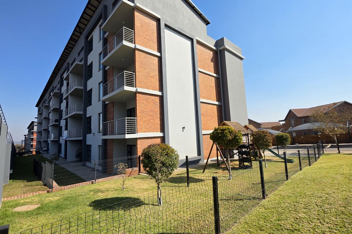 Exterior view of a modern apartment building featuring brick and plaster facade, private balconies with metal railings, and a well-maintained communal garden area.