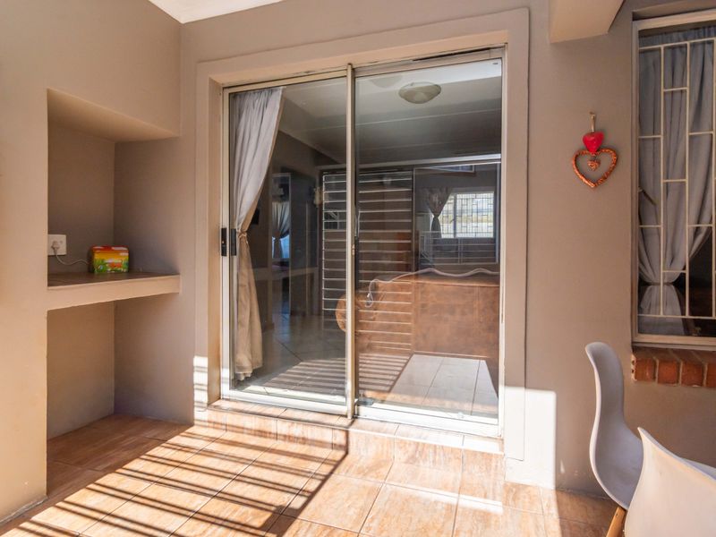 A covered patio area featuring tiled flooring, a built-in concrete shelf, and a sliding glass door providing access to the interior living space.