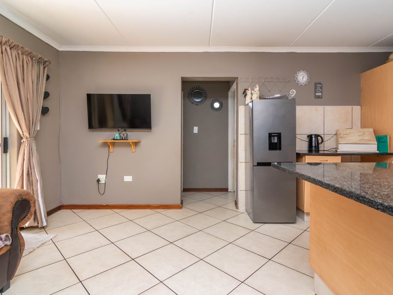 Open plan living and kitchen area featuring tiled flooring, granite countertops, and direct access to an outdoor space via a sliding glass door.