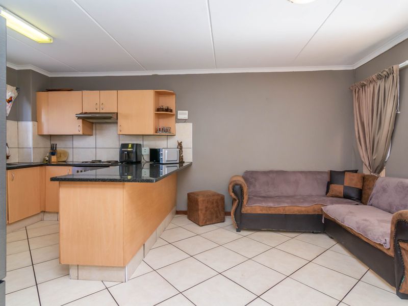 Open-plan living area featuring a kitchen with laminate cabinetry, granite countertops, and tiled flooring, seamlessly flowing into the adjacent lounge space.