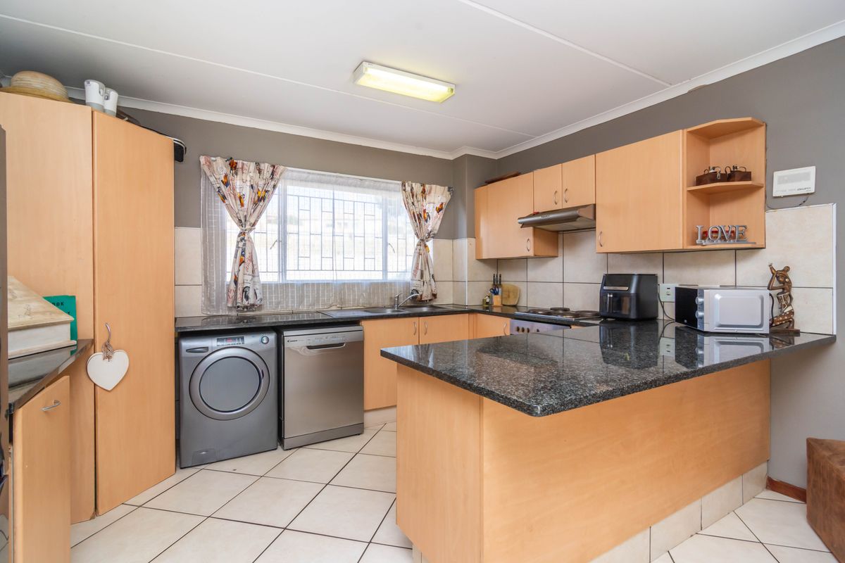 A functional kitchen featuring laminate cabinetry, granite countertops, tiled backsplash, and integrated space for laundry appliances.
