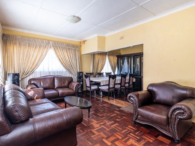 Open-plan living and dining area featuring traditional parquet flooring and a built-in display cabinet, requiring some ceiling maintenance.