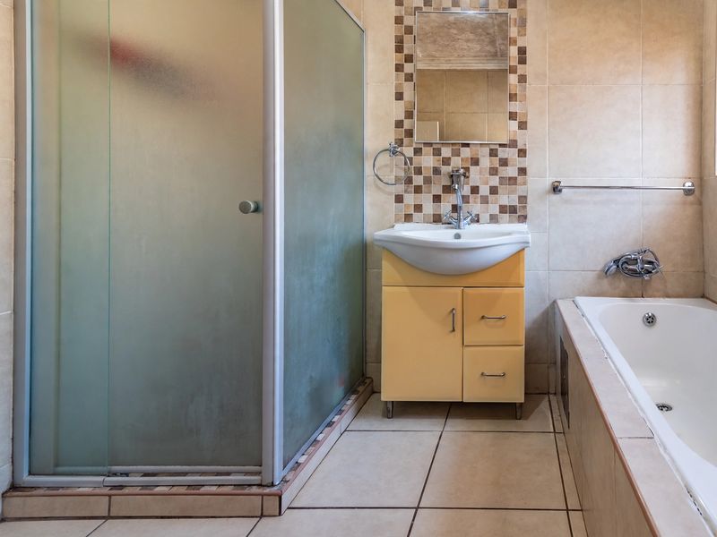 A functional bathroom featuring a shower enclosure, a built-in bathtub, and a vanity basin with tiled wall finishes.