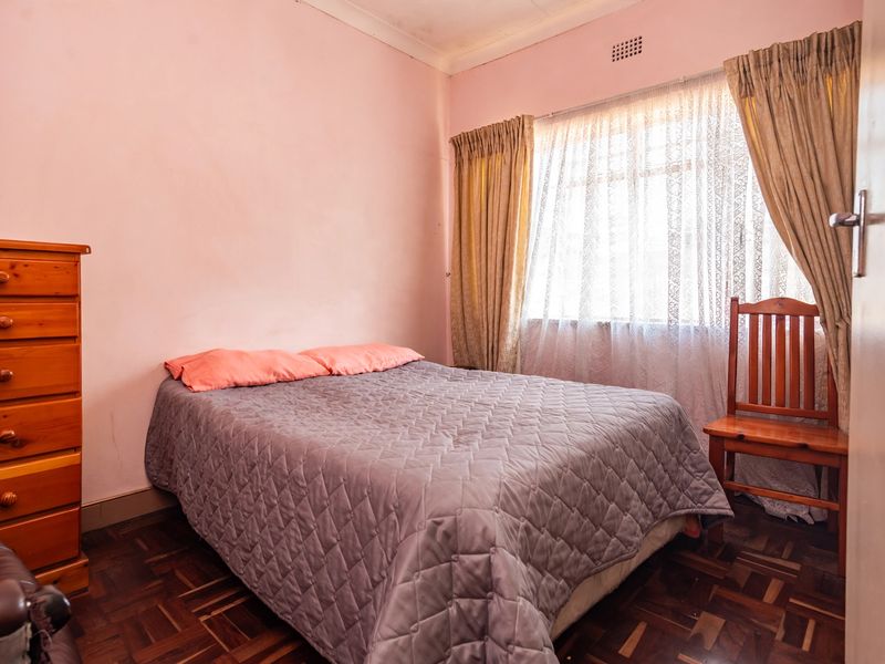 A bedroom featuring parquet flooring and a ventilation grille, requiring cosmetic updates to the walls and ceiling to improve the overall aesthetic.