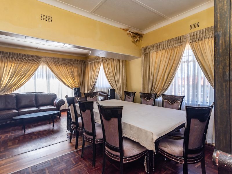 Open plan living and dining area featuring parquet flooring and coved ceilings, currently showing signs of significant water damage on the ceiling.