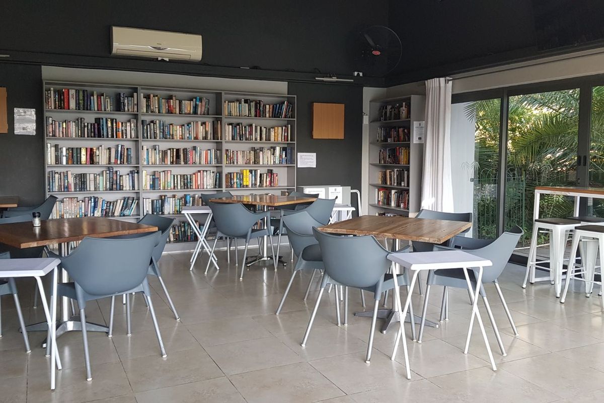 A spacious living area featuring extensive built-in bookshelves, tiled flooring, and large sliding glass doors providing natural light and garden access.