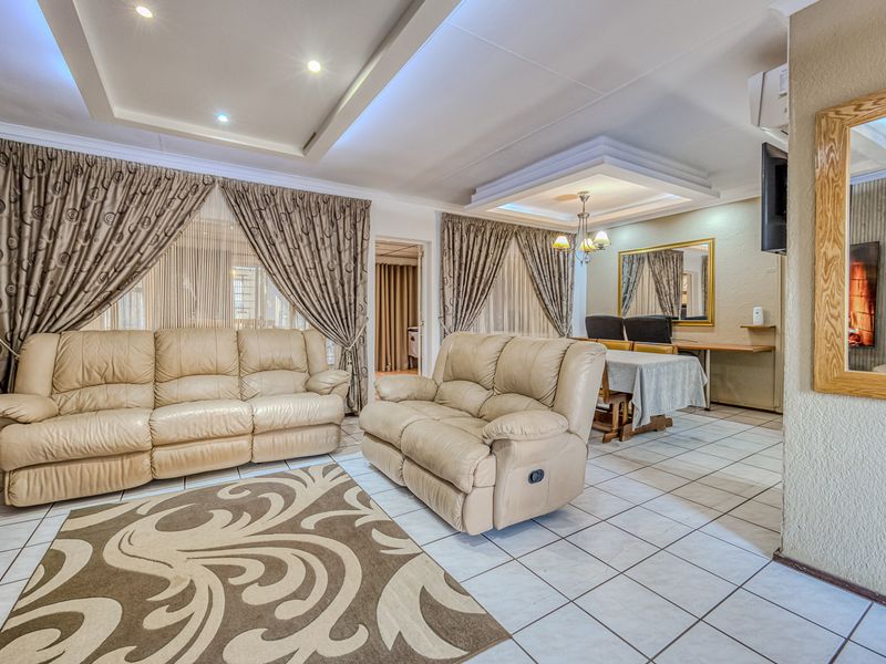 Spacious open-plan living and dining area featuring tiled flooring, recessed ceiling lighting, and a coved ceiling design.