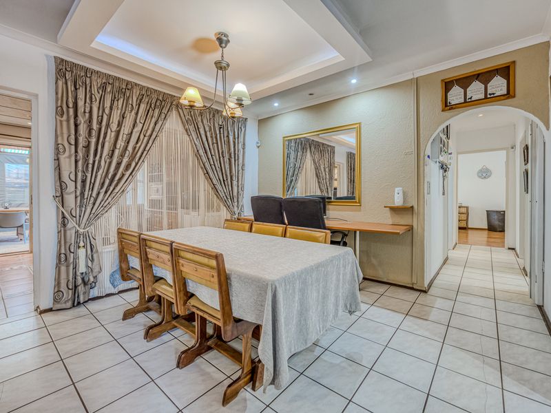 Dining room featuring tiled flooring, a recessed ceiling, and an arched entryway leading to a hallway, with an adjacent sliding door to the patio.