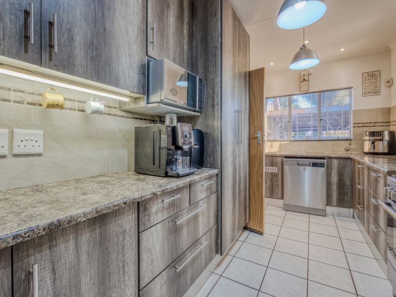 Modern kitchen featuring wood-look laminate cabinetry, granite countertops, tiled backsplash, and integrated appliances including a gas stove and dishwasher.