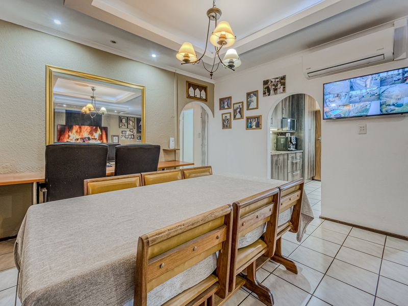 Dining area featuring tiled flooring, a recessed ceiling, and an archway leading to the kitchen, with a wall-mounted air conditioning unit.