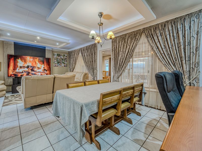 Spacious open-plan living and dining area featuring tiled flooring, a recessed ceiling design, and large windows with integrated curtain treatments.