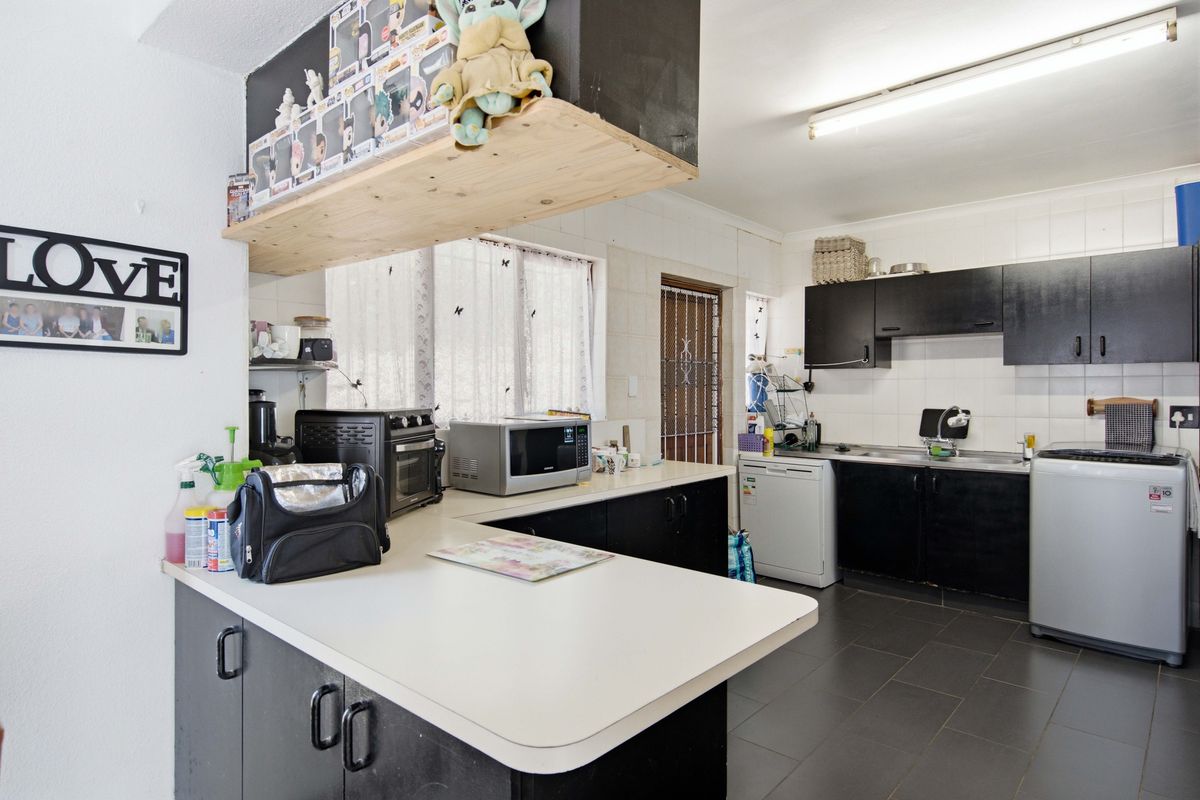 A functional kitchen featuring dark cabinetry, laminate countertops, tiled backsplash, and tiled flooring, offering a practical layout for daily meal preparation.