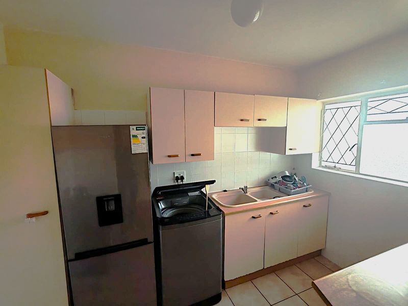 A functional laundry area featuring built-in cabinetry, a double basin sink, and tiled splashbacks, providing practical utility space.